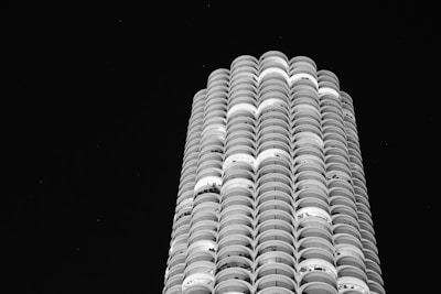 The exterior of a high-end residential tower with illuminated balconies against a twilight sky.