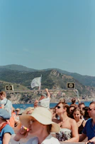 A family enjoying a sunny day aboard a rented boat with scenic coastline in the background.