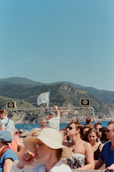 A vibrant group of people enjoying a boat tour along the stunning coastline of Costa degli Dei under a bright blue sky.