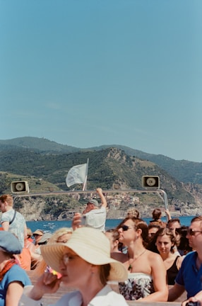 Tourists enjoying a sunny day on a boat, with clear blue waters around.