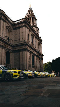 A lineup of shiny police cars with flashing lights parked outside a studio.