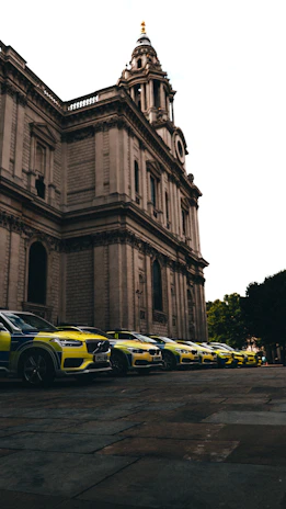 A lineup of realistic police cars, firetrucks, and ambulances ready for filming on a studio lot.