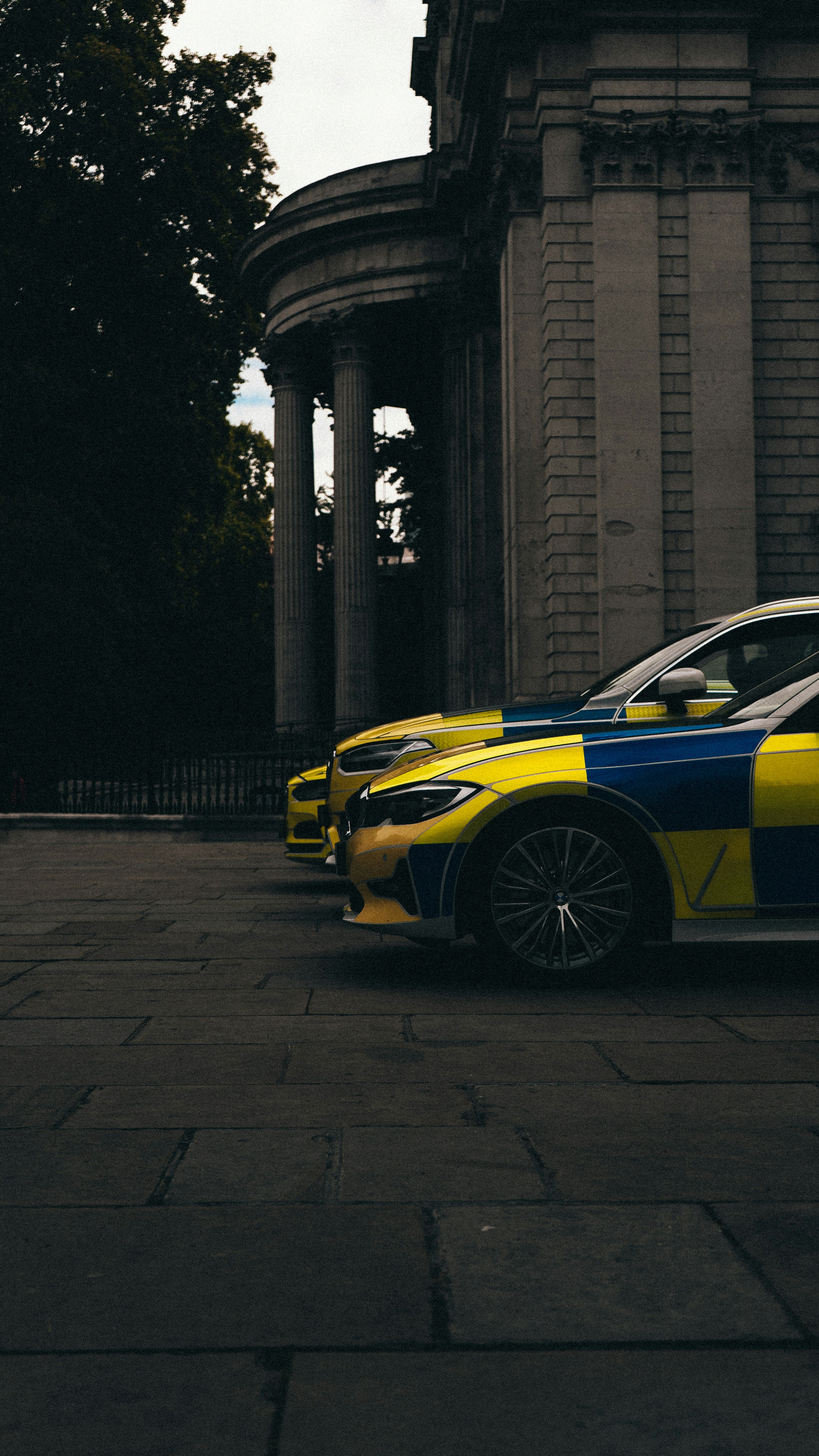 a yellow and black sports car parked in front of a stone building
