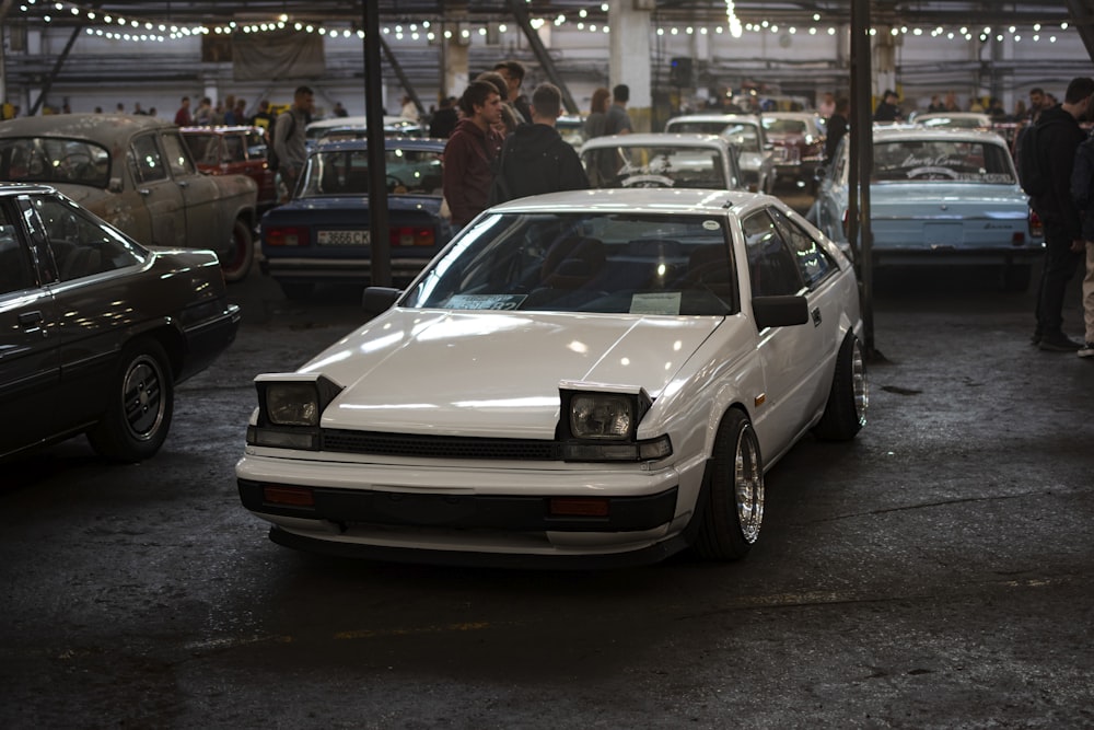 a white car parked in a parking lot with other cars