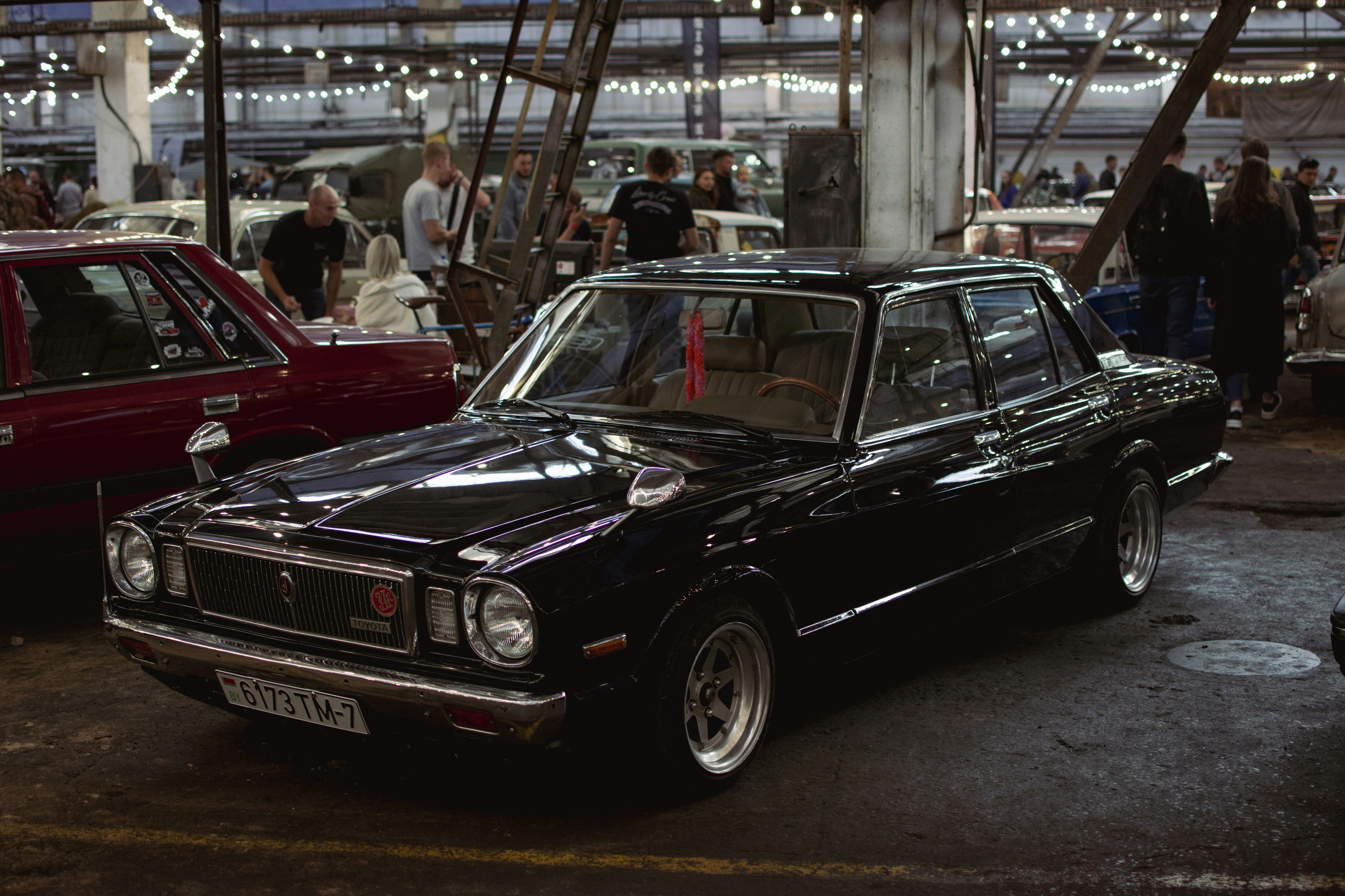 a black car parked in a showroom with people standing around
