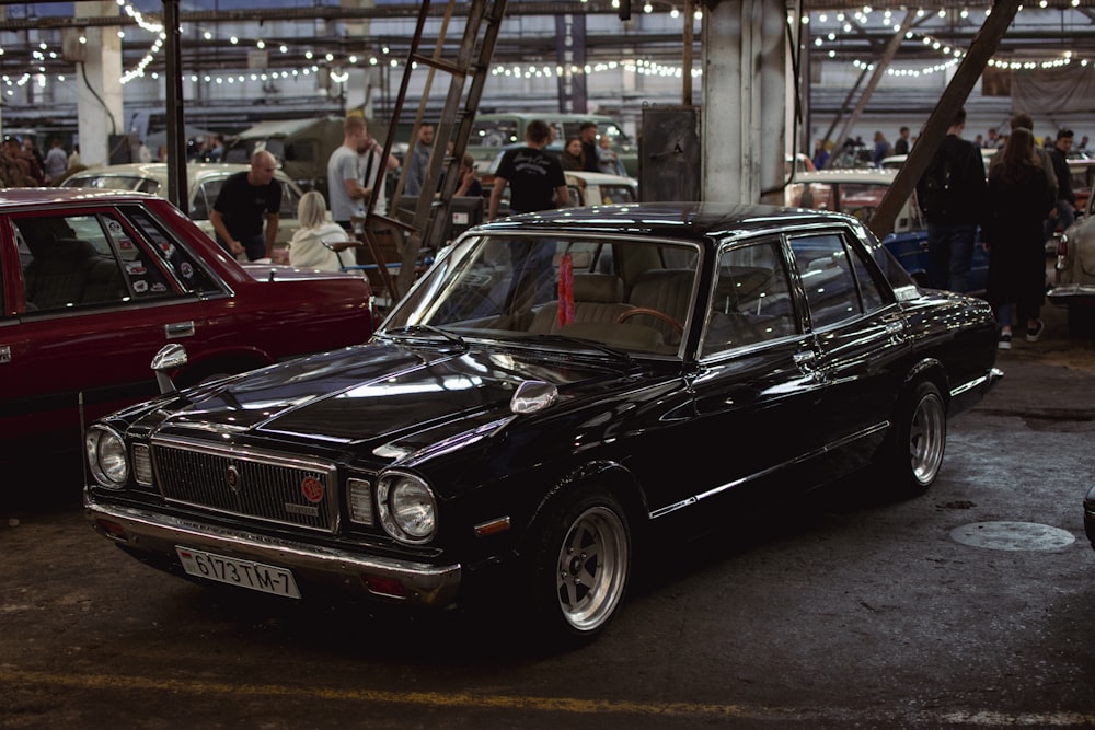 a black car parked in a showroom with people standing around