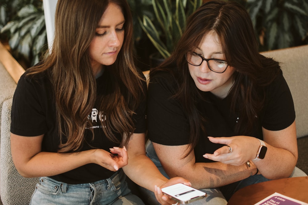 a couple of women looking at a phone