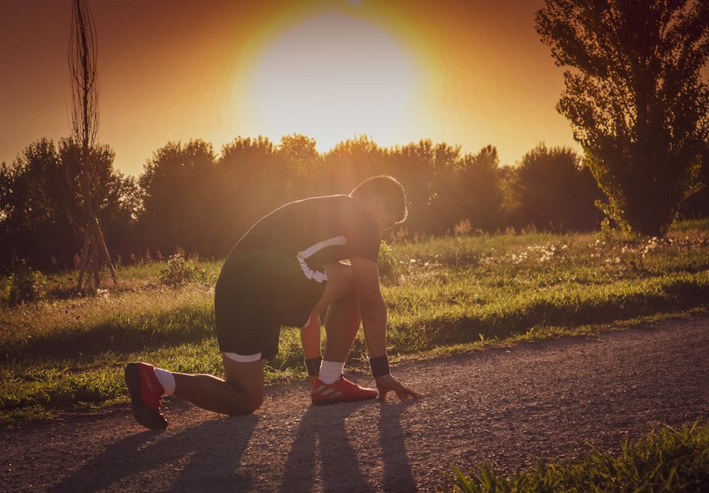 a person kneeling on a dirt road