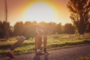 An athletic creator stretching before a run along a scenic Scottish trail at dawn