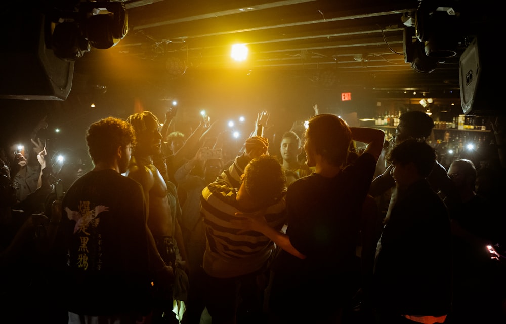 a group of people dancing in a dark room with bright lights