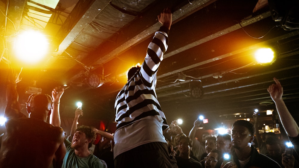 a person holding the arms up in front of a crowd of people