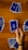 A hand holds a playing card with Arabic text printed on it. Several other cards are spread out on a wooden surface in different positions.