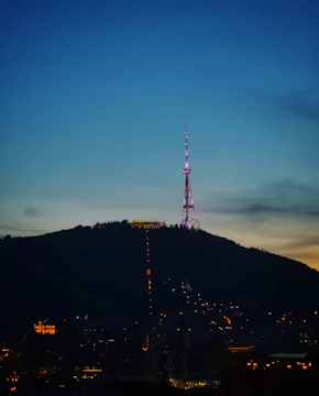 Radio tower glowing against a twilight sky, symbolizing broadcast reach.