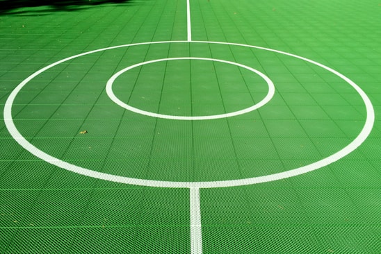 A vibrant tennis court bathed in sunlight with neon yellow-green accents highlighting the net and lines.