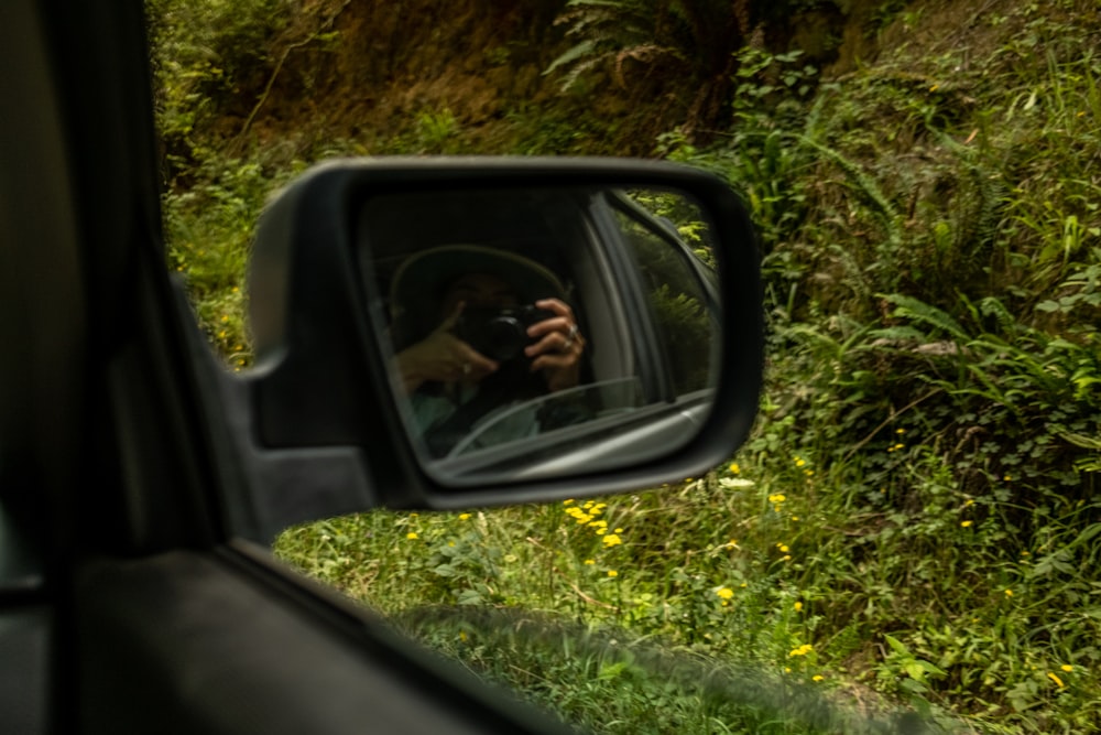 a person taking a picture of themselves in a car mirror