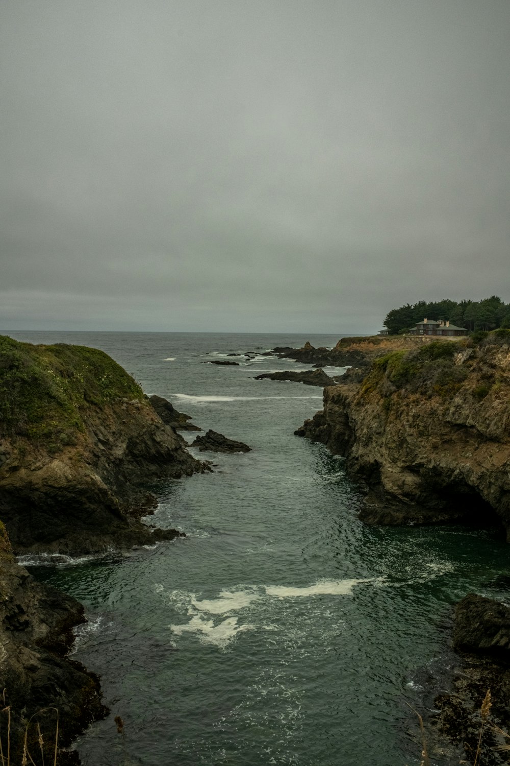 a rocky beach with a body of water and a house on the shore