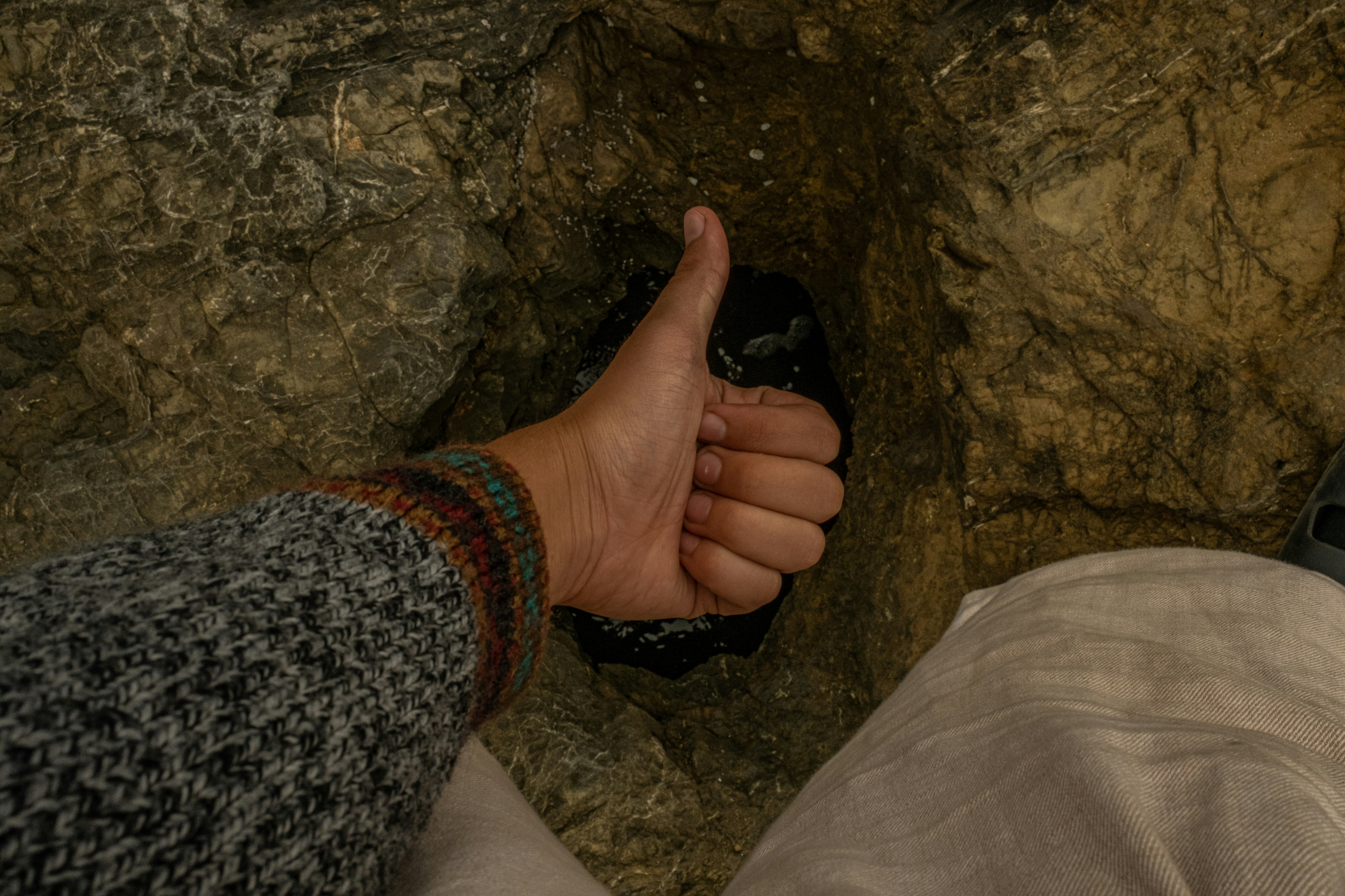 a person's hand holding a black object in front of a rock
