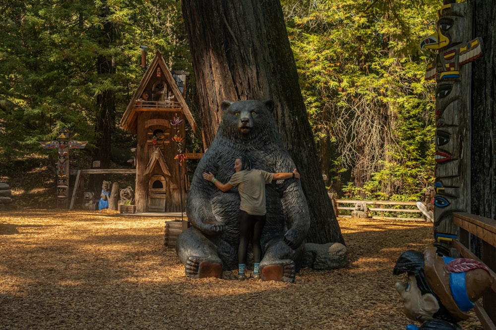 a person standing next to a large bear statue