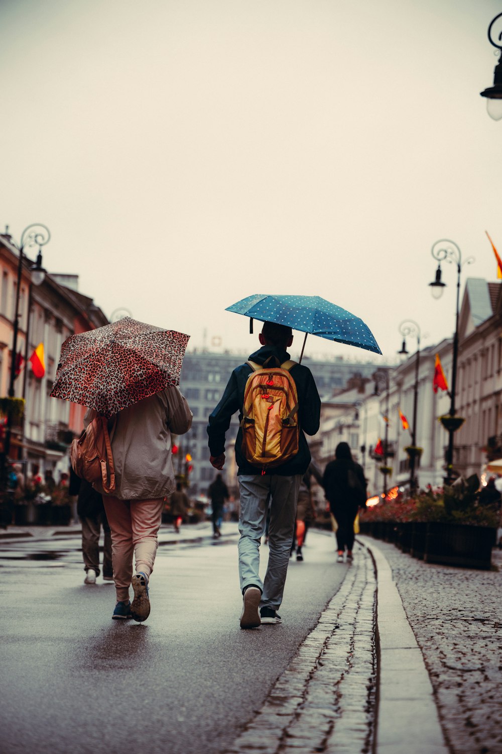 people walking down a sidewalk with umbrellas