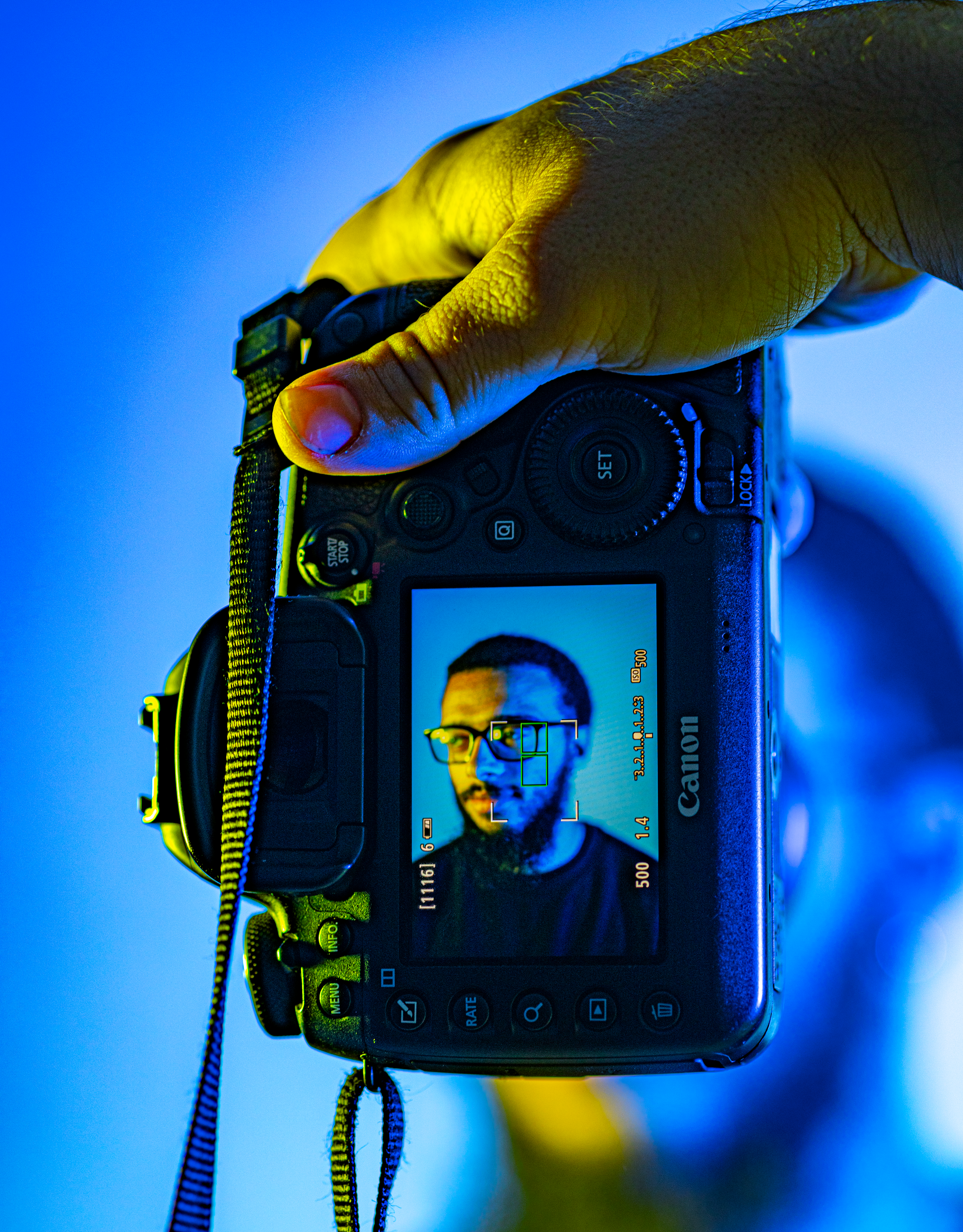Mano che tiene una fotocamera digitale con il ritratto di un uomo barbuto.