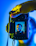 A hand holding a Canon camera with a live view screen displaying a portrait of a man wearing glasses. The background is a vibrant mix of blue and yellow tones, creating a striking contrast with the camera's black exterior.
