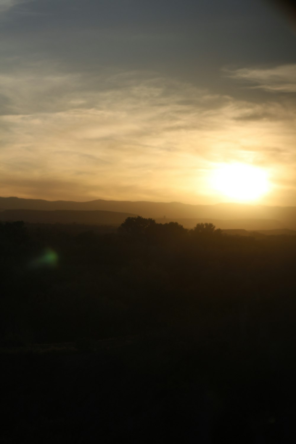 a landscape with trees and the sun in the background