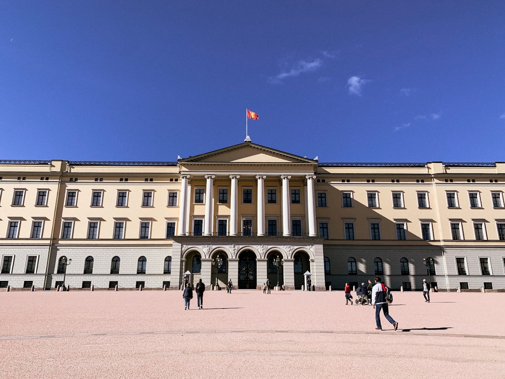 a large building with a flag on top with Royal Palace, Oslo in the background