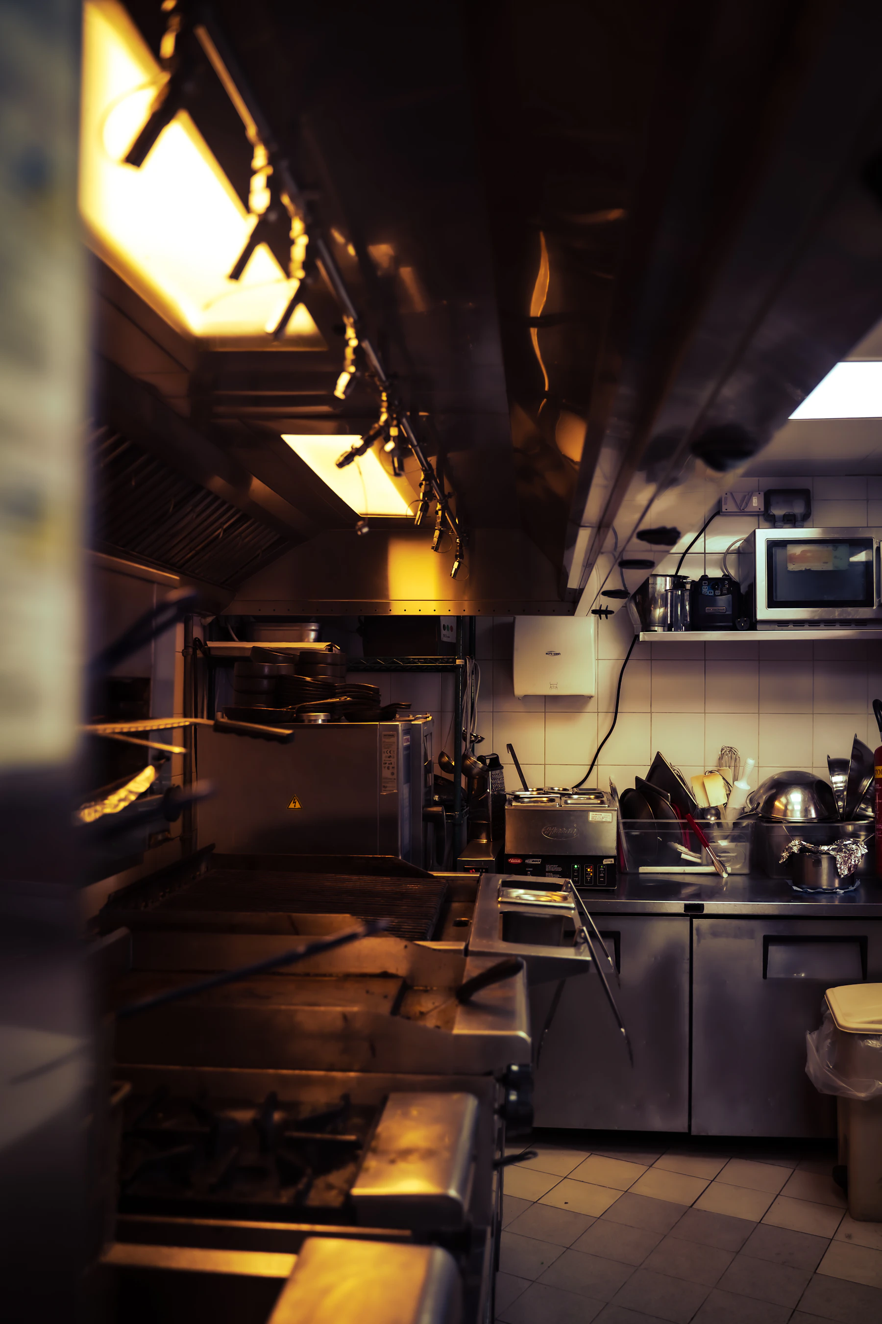 Cinematic back-of-house restaurant kitchen with professional cooking equipment