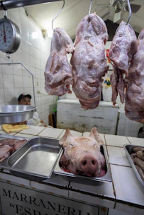 Close-up of fresh pork cuts displayed on rustic wooden boards in a butcher shop.