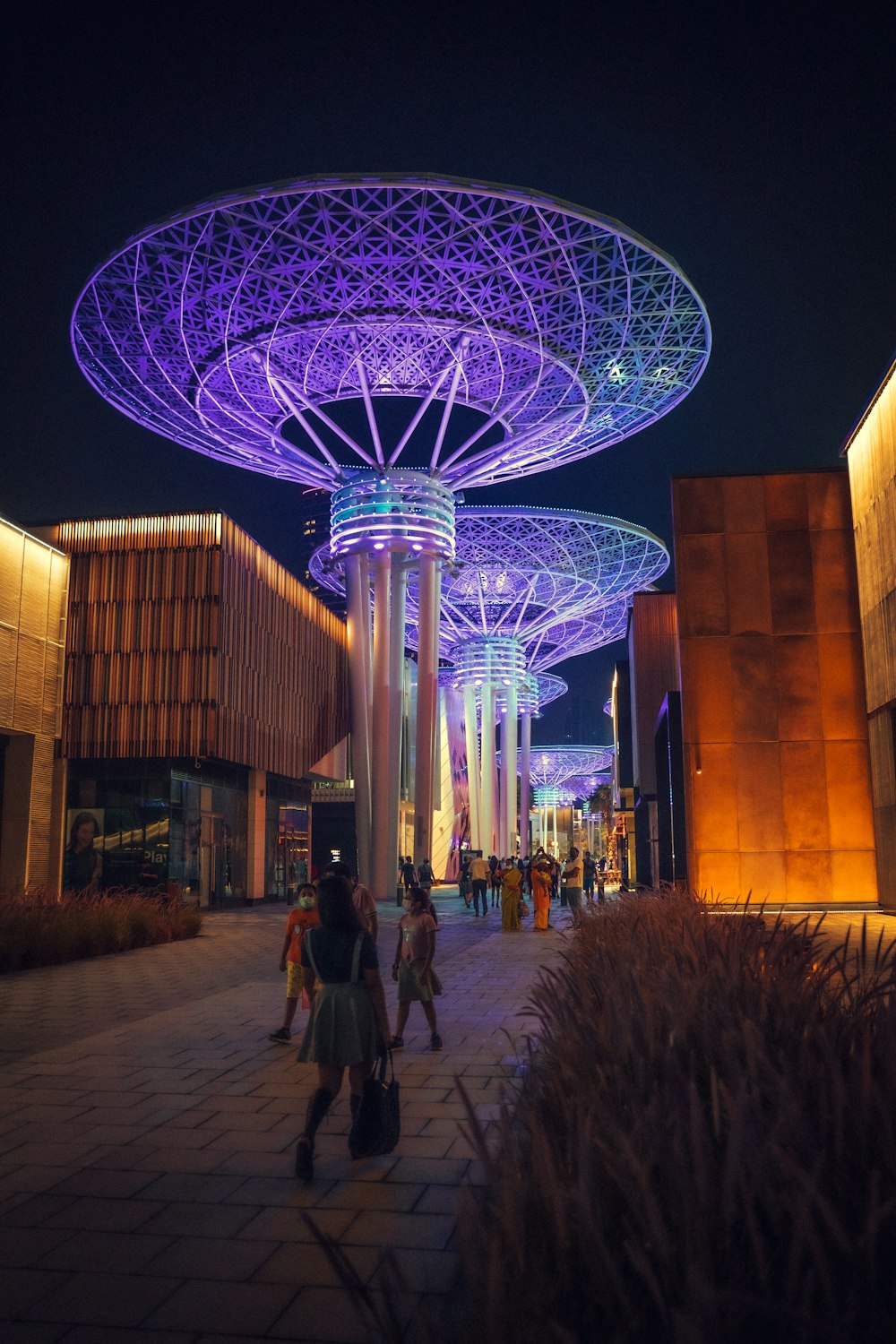 people walking on a sidewalk with a ferris wheel in the background