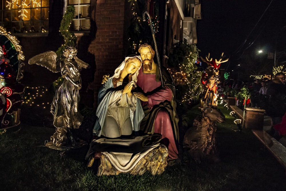 a statue of a person sitting on a throne surrounded by christmas trees