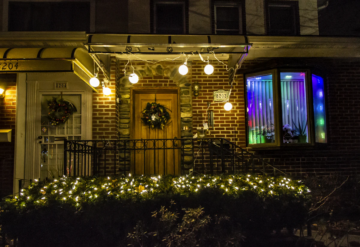 Home porch with warm white string lights, a wreath, and color-changing RGB accent lighting in the window