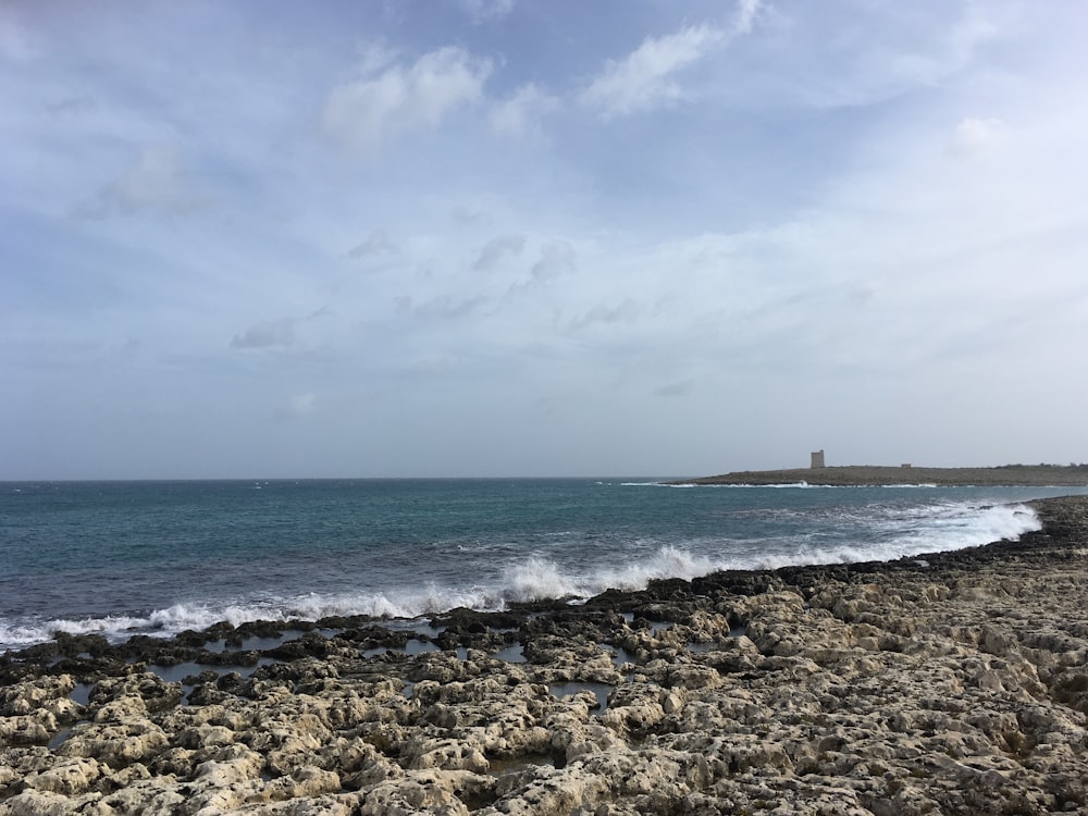 a rocky beach with a lighthouse in the distance