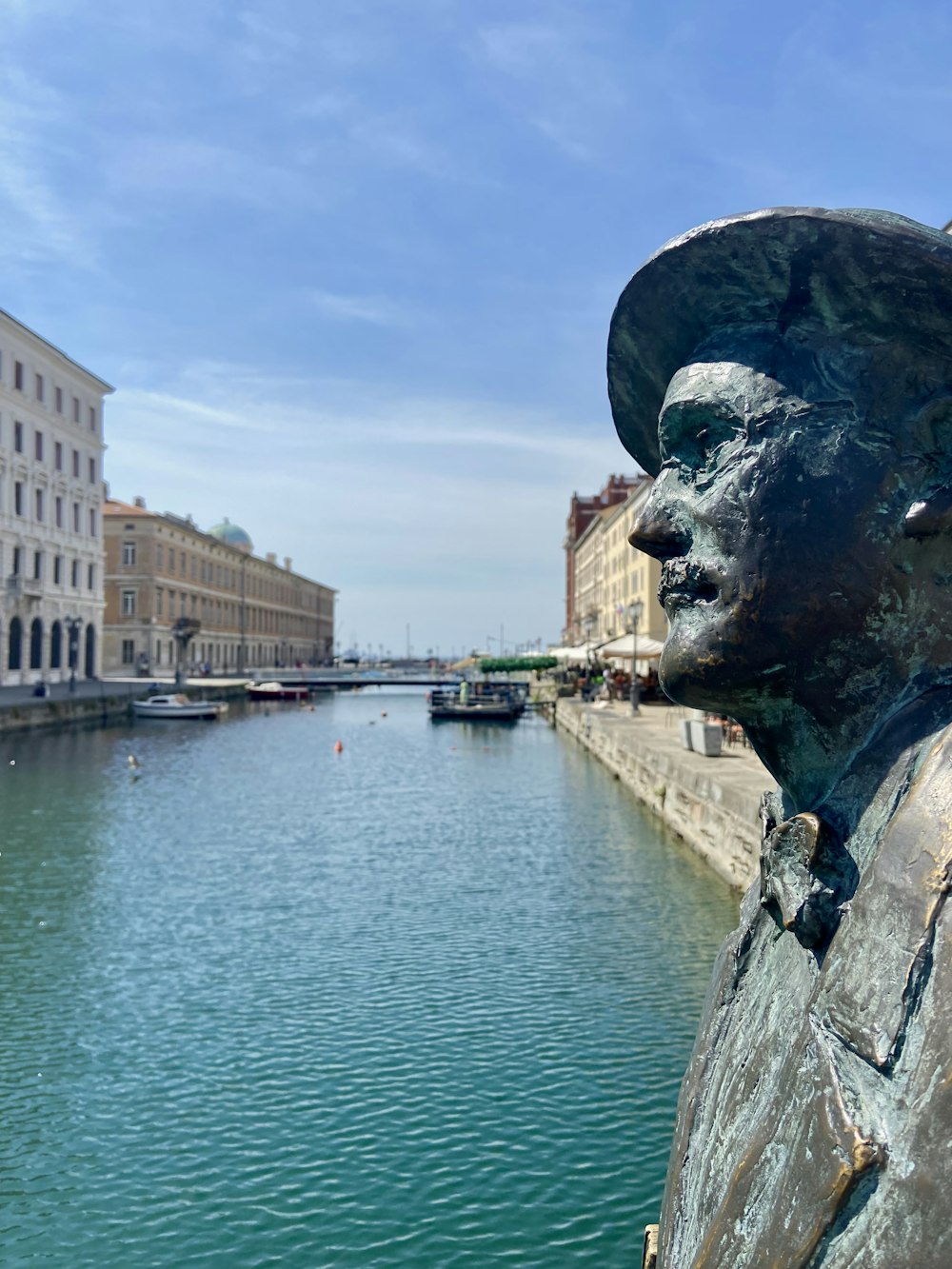 a statue of a person by a river with buildings and boats