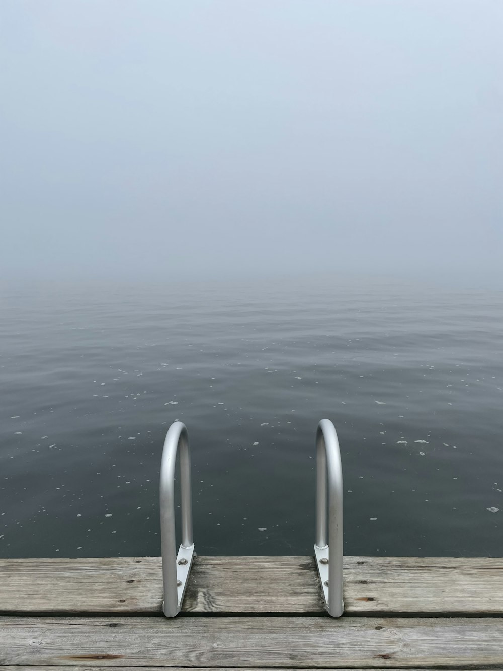 a dock with a railing and a body of water in the background