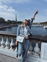 a person sitting on a railing with the arms up and a body of water in the background