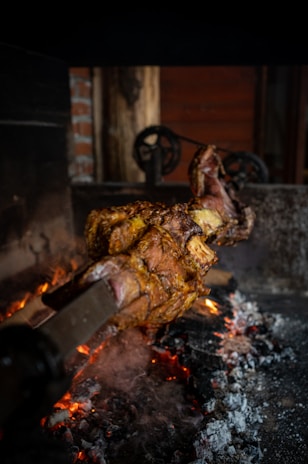 A chef skillfully roasting a whole suckling pig over an open flame at an outdoor wedding barbecue.
