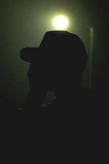 A cinematic night scene featuring a steampunk hat illuminated by soft metallic glints and deep shadows.