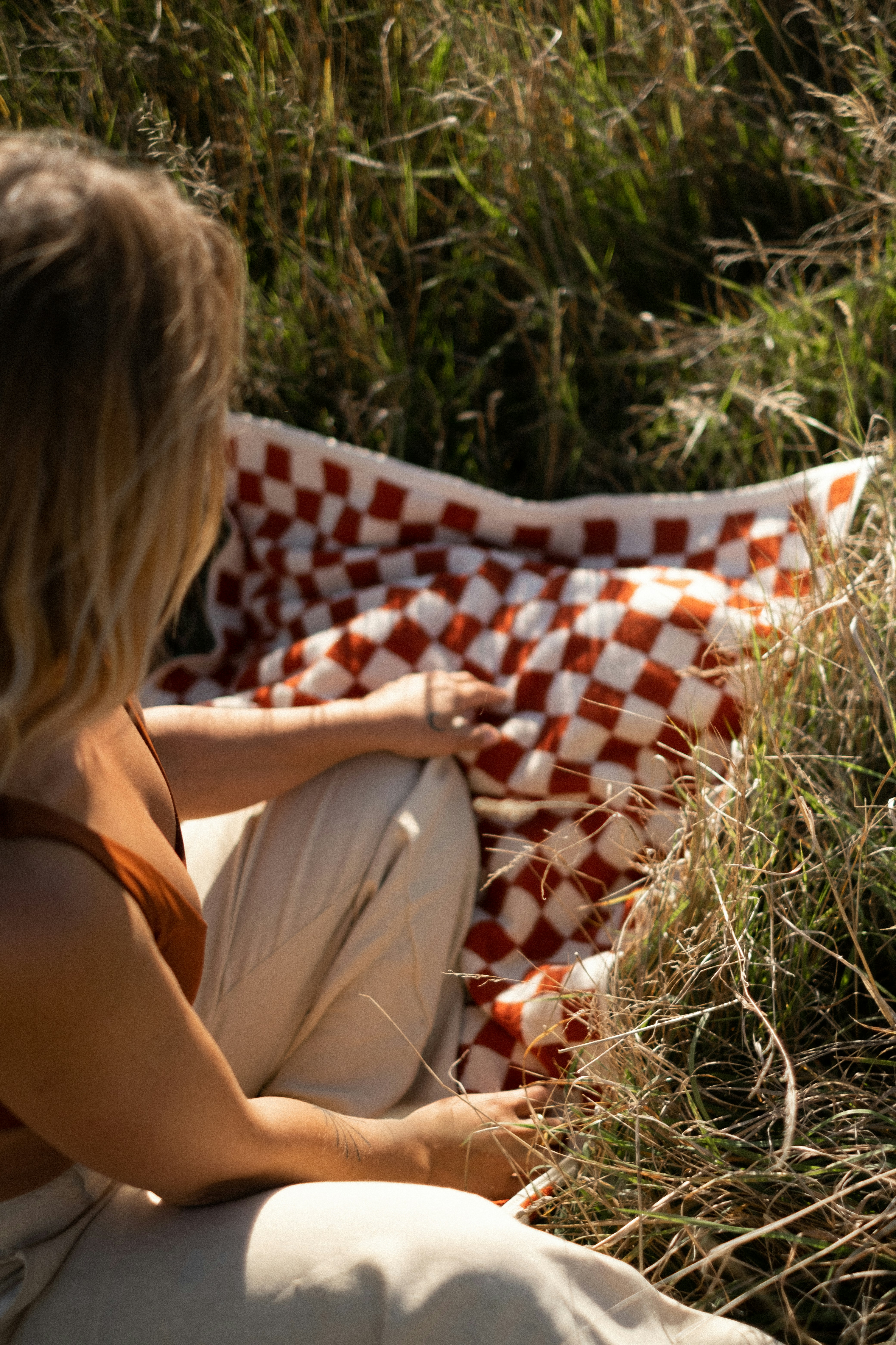 a woman sitting on a blanket in the grass