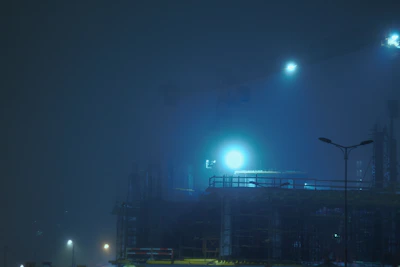 Nighttime shot of a well-lit construction site with cranes and machinery.