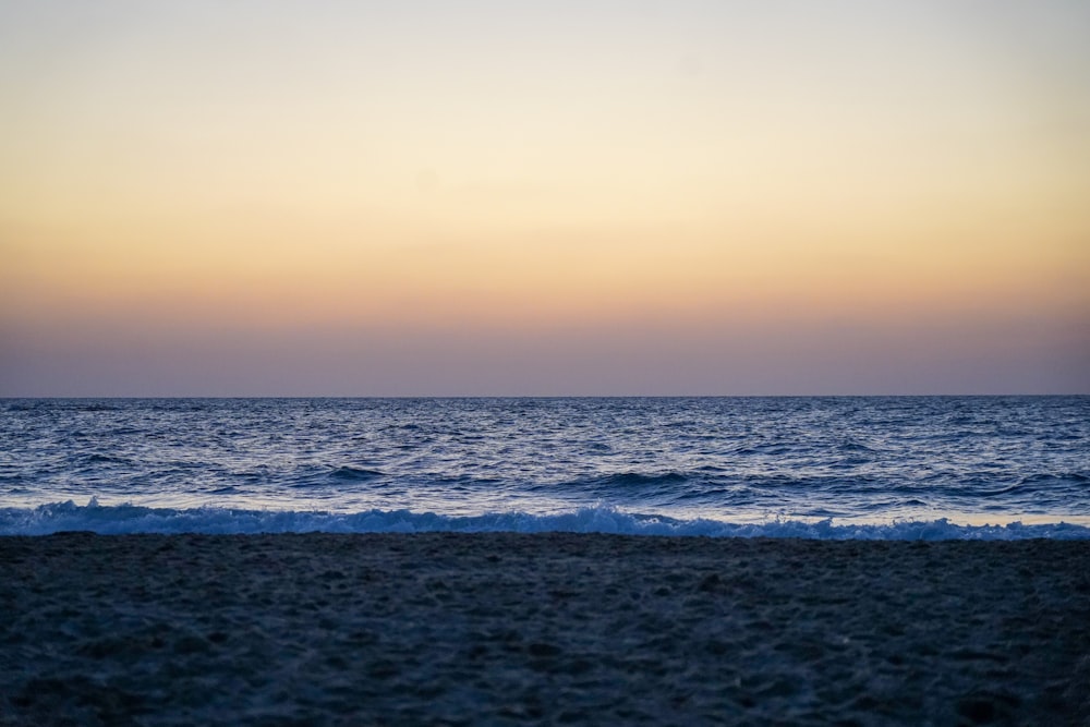 a beach with waves and a sunset