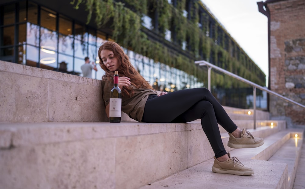 a person sitting on a ledge holding a bottle of alcohol