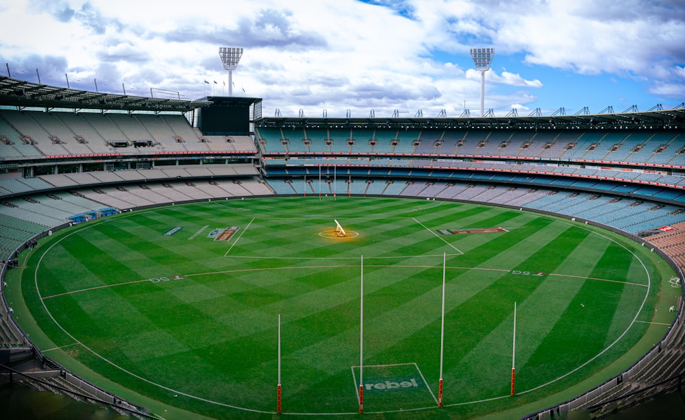 a sports stadium with a field and a field with a crowd of people with Melbourne Cricket Ground in the background