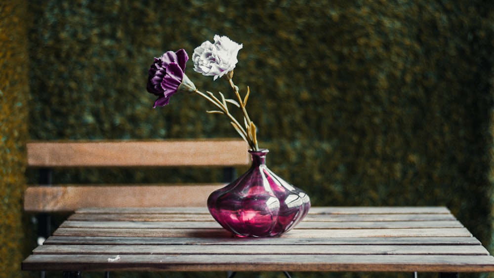 a vase with flowers on a bench