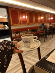 A steaming cup of coffee next to a plate of Turkish delight.