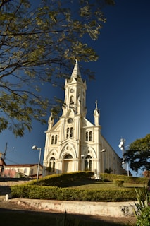 A warm, inviting photo of the Lady of Lebanon Maronite Catholic Church bathed in soft sunlight with subtle Lebanese cedar tree motifs in the background.
