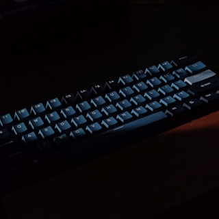 A modern mechanical keyboard with backlit keys glowing in a dim room.