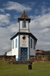 a small white building with a blue door and a cross on top