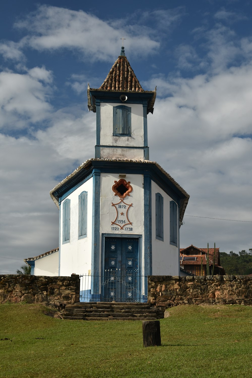 a small white building with a blue door and a cross on top