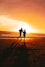 a couple of people running on a beach at sunset